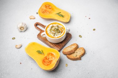 Kızarmış çekirdekli kremalı balkabağı çorbası, sarımsak, otlar ve hafif desenli ekmek..