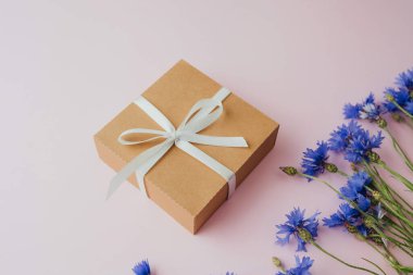 Pembe arka planda hediye kutusu ve çiçek.