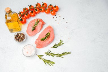 Beyaz arka planda baharatlı dana bifteği ve bitkilerin üst görüntüsü, yakın plan yağ ve biber dahil.