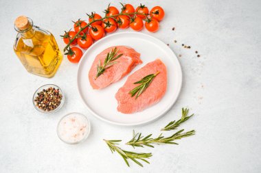 Baharat ve sebzelerle çevrili, beyaz tabakta biberiyeli iki dana biftek.