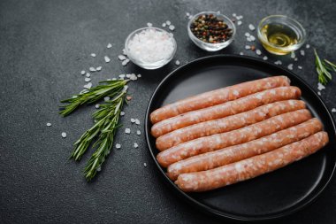 Siyah tabakta çiğ domuz sosisi ve biberiye.