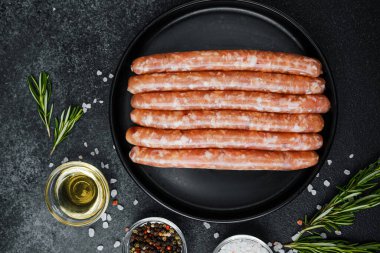 Siyah tabakta çiğ domuz sosisi ve biberiye.