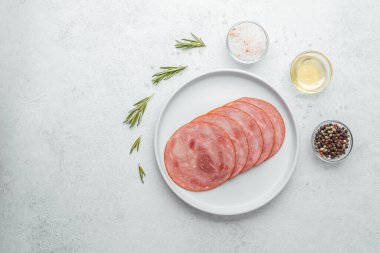 Beyaz tabakta dilimlenmiş sosis ve baharat.