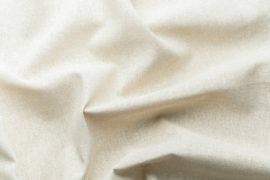 Yumuşak kıvrımlı ve desenli doğal bej kumaş.