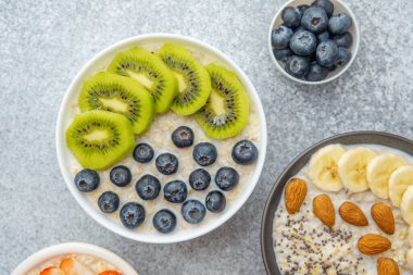 Yabanmersinli yulaf ezmesi ve gri taşlı arka planda beyaz kasede kivi.