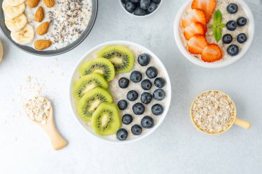 Beyaz arka planda meyveler ve yulaflı yulaf ezmesi kaseleri.