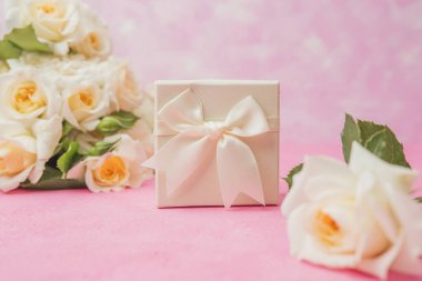 Saten kurdeleli ve gül buketli zarif beyaz hediye kutusuna yakın çekim