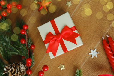 Kırmızı kurdeleli bayram hediyesi kutusu, çam dalları, kutsal üzümler ve kırsal yüzeyde mumlar.