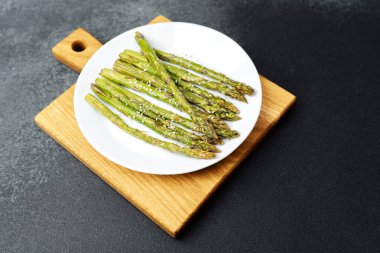 Hafif baharatlı tabakla süslenmiş taze kuşkonmaz..