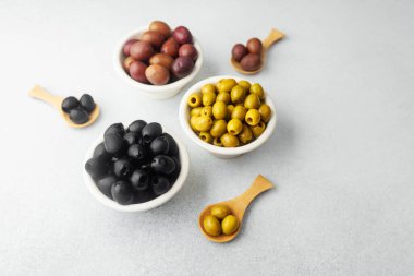 Gri arkaplandaki zeytinler, yeşil zeytinler, siyah ve kalamata zeytinleri.