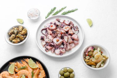 Deniz ürünleri markalaşması veya ambalaj konsepti için beyaz zemin üzerinde biberiye ve sos bulunan bir kase ahtapot.