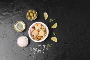 Minimalist gurme ya da malzeme tasarımı konsepti için siyah masa üzerinde limon ve şifalı deniz ürünleri kasesi.