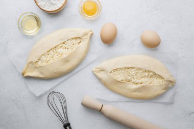 Işık yüzeyinde peynirli ve yumurtalı iki çiğ khachapuri.