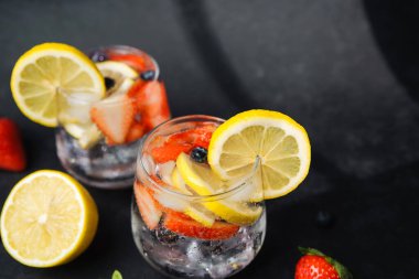 Limonata bardakları, limon çilekleri ve yaban mersinleriyle kaplanmış koyu renkli meyve parçaları.