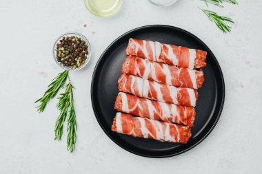 Domuz pastırması siyah tabakta baharat ve biberiye ile sarılmış.