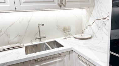 Lüks modern mutfak, beyaz mermer tezgah, temiz çelik lavabo, zarif dolaplar, ortam aydınlatması, dekor..