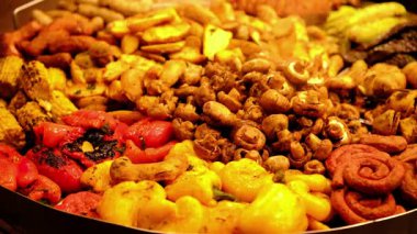 Açık büfe için büyük bir servis tabağında lezzetli kavrulmuş sebzeler ve spiral sosisleri yakından izleyin.