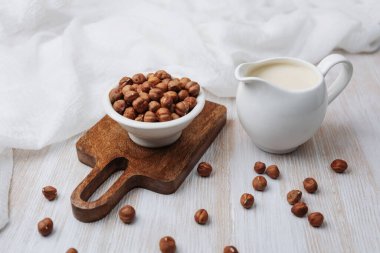 Fındık ve kremalı süt beyaz kumaşlı tahta bir sürahide.