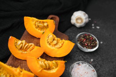 Sarımsaklı, biberli, turuncu balkabağı parçaları ve ahşap bir tahtada pembe tuz.