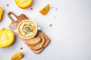 Kremalı balkabağı çorbası ve tahtadan yapılmış tohumlar kızarmış ekmek ve taze balkabağı dilimleri.