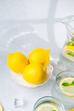 Dekoratif beyaz tezgahta sergilenen taze sarı limonlar açık arkaplanda gölgeler olan parlak güneş ışığında