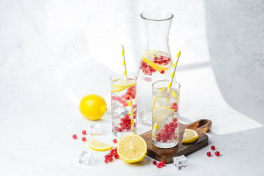 Limon dilimleri ve sarı çizgili kamışlarla servis edilen kırmızı meyveli içecek.