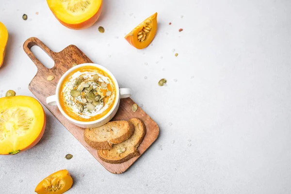 Kremalı balkabağı çorbası ve tahtadan yapılmış tohumlar kızarmış ekmek ve taze balkabağı dilimleri.