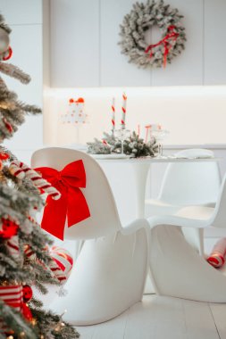 Kırmızı kurdeleli ve bastonlu beyaz şenlikli sandalyeler süslü bir ağacın yanında bir bayram yemeği bekliyor..