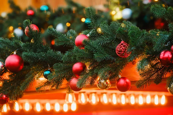 Canlı kırmızı, altın, gümüş tatil toplarıyla süslenmiş Evergreen dalları ışıl ışıl ışık saçıyor.