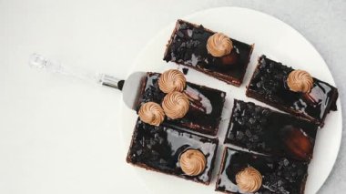 Kek sunucusuyla servis edilen beyaz tabakta kremalı pasta dilimleri.