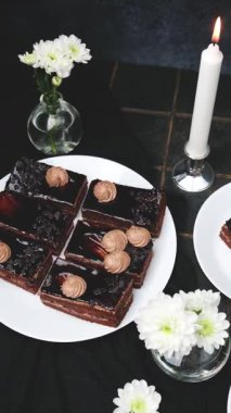 Tabakta kremalı pasta, beyaz çiçekler, masada yanan mum.