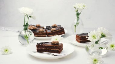 Temiz beyaz bir masada beyaz çiçeklerle dilimlenmiş lezzetli çikolatalı pasta.