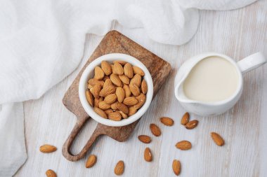 Badem ve organik bitki sütü beyaz kumaşlı tahta bir sürahide.