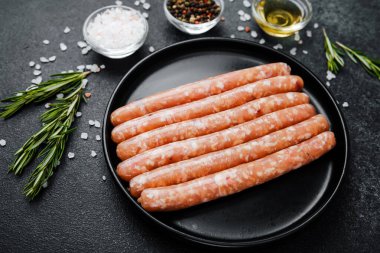 Siyah tabakta çiğ domuz sosisi ve biberiye.