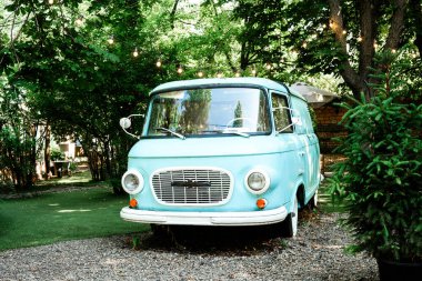 Seyahat ve eski yaşam tarzı stok konsepti için yaz bahçesinde peri ışıkları olan klasik mavi bir minibüs.