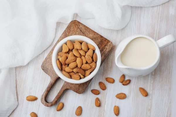 Badem ve organik bitki sütü beyaz kumaşlı tahta bir sürahide.