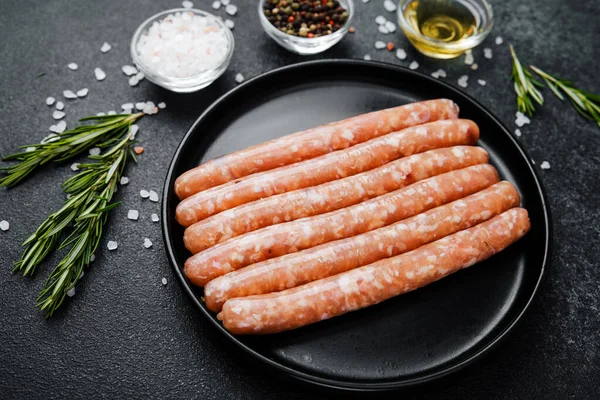 Siyah tabakta çiğ domuz sosisi ve biberiye.