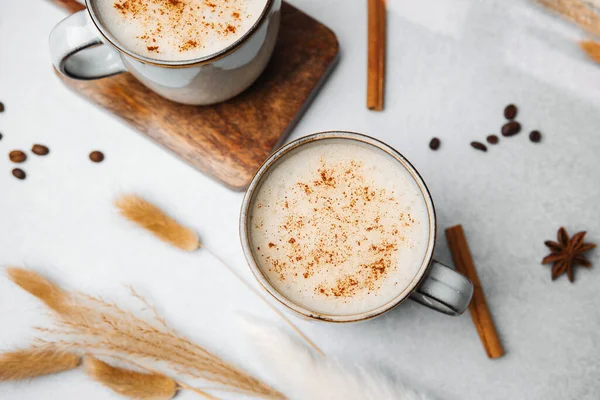 Hafif desenli baharatlı bir yüzeyde tarçınla kaplı ılık kremalı kahve içecekleri.