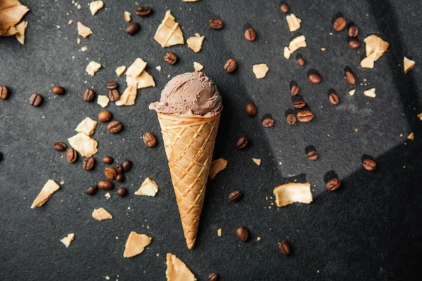 Kahveli dondurma külahı ve siyah arka planda waffle kırıntıları.
