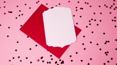 Zarif pembe arka plan, dağınık kalpler, kırmızı zarf ve Sevgililer Günü için boş kart.