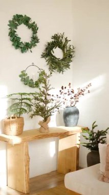 Doğal çelenkler ve bitkiler kapalı alandaki ahşap bir konsol masasını süsler..