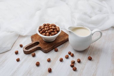 Fındık ve kremalı bitki sütü beyaz kumaşlı tahta bir sürahide.