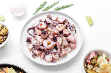 Deniz ürünleri markalaşması veya ambalaj konsepti için beyaz zemin üzerinde biberiye ve sos bulunan bir kase ahtapot.