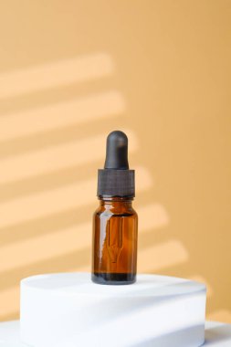 Kehribar cam serumu şişesi bej rengi taş kaidede.