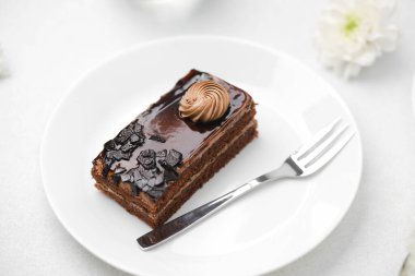 Çürümüş çikolatalı pasta dilimi, parlak jöleli ve çatallı beyaz tabak, tatlı tatlı