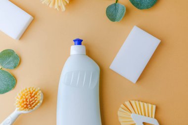 Temiz beyaz sünger şişe fırçası ve bej yüzeyde yeşil yapraklar.