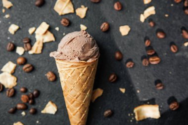 Kahveli dondurma külahı ve siyah arka planda waffle kırıntıları.