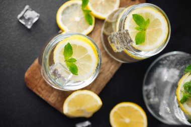 Limonata, limon dilimleri ve şeffaf cam sürahide nane yapraklarıyla güneş ışığı altında limonata tazeleniyor.