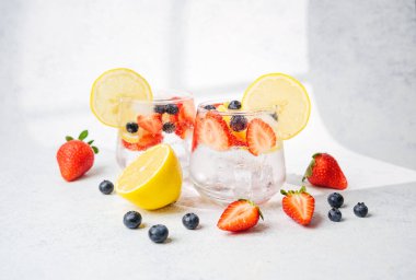 Limon dilimli köpüklü limonata. Çilek ve yabanmersini. Koyu arka planda.