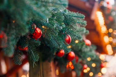 Yeşil çam ağacı dalları parlak kırmızı toplar ve tatil için sıcak bokeh ışıkları ile süslenmiş.